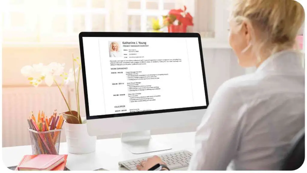 a person sitting at a desk with a resume on their computer